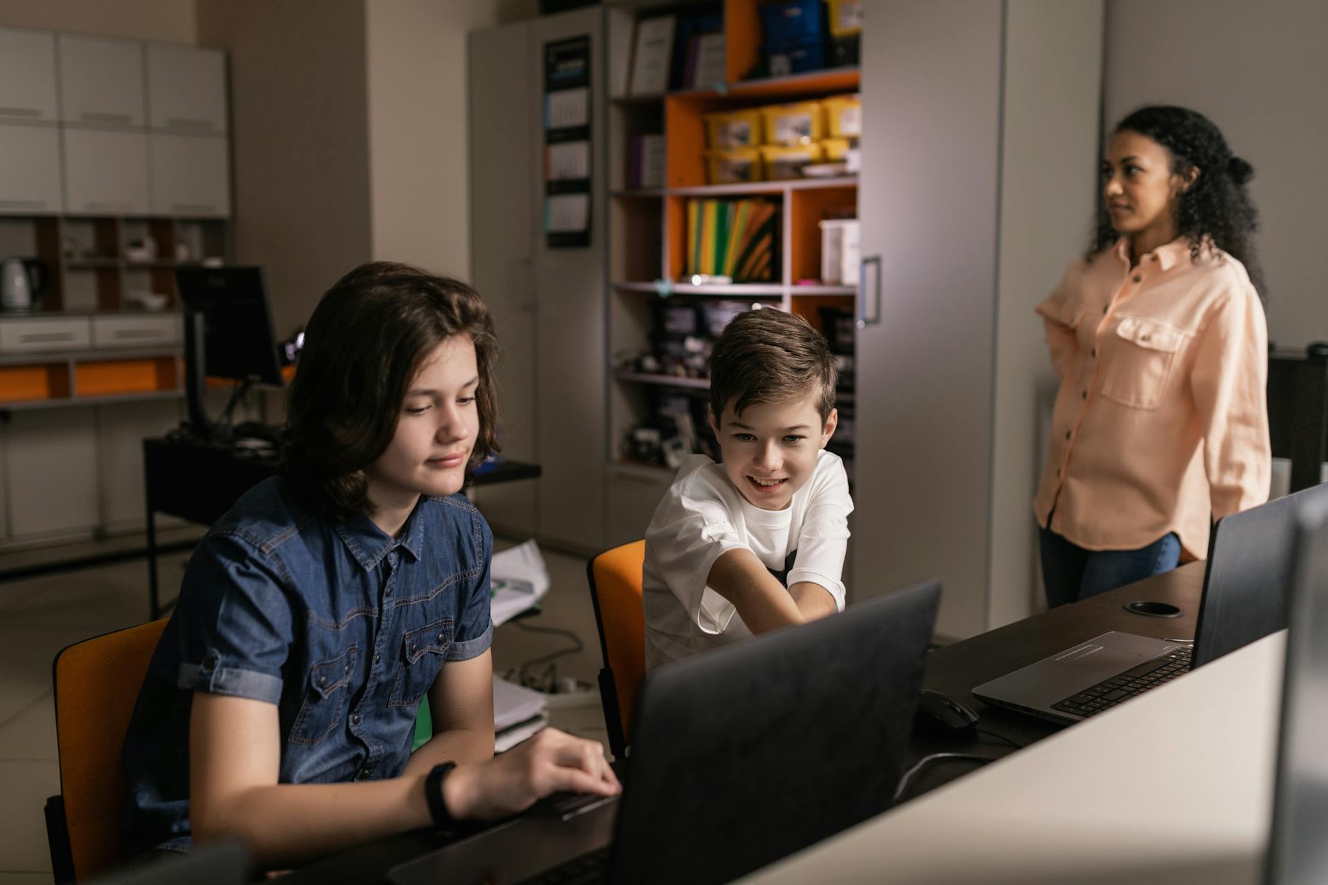 Profesora supervisando a alumnos que trabajan con sus portátiles en clase